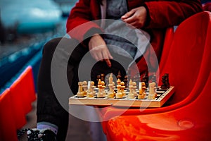 Close up of chess on stadium bleacher. Body part of unrecognizable woman playing in board game in cold weather.