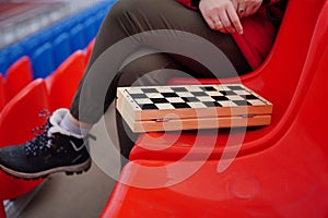 Close up of chess on stadium bleacher. Body part of unrecognizable woman playing in board game in cold weather