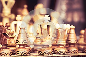 Close up of chessboard with wooden pieces on table in sunlight. Chess game, close up image with selective focus