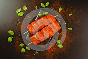 Food concept.Chicken breast Fillets.Fresh raw marinated chicken fillet skewers with fresh herbs on a black background