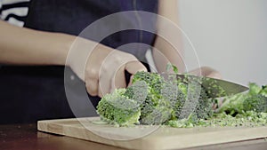 Close up of chief woman making salad healthy food and chopping broccoli on cutting board