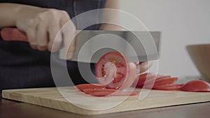 Close up of chief woman making salad healthy food and chopping tomato on cutting board in the kitchen