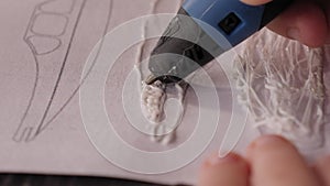 Close-up of child creates a new 3D object using a 3D pen from a robotics school.