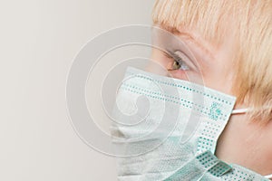 Close up of child face in surgical mask, white background. Prevention of bacterial infection Covid 19 photo