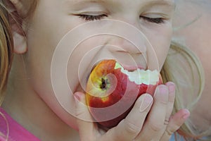 Close up Child Girl Eating Organic Apple in Orchard. Harvest Concept. Garden, Toddler eating fruits at fall harvest