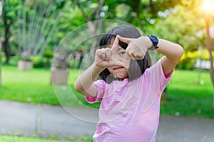 Close up of child girl smiling making frame with hands and fingers. Creativity and photography concept