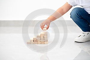 Close up child hand arranging wood block stacking as step stair.