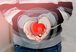 Close up of child hands holding red heart. Cardiology concept