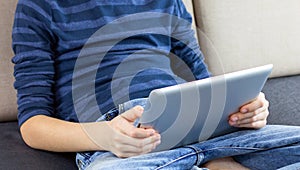 Close-up child hands with a tablet. Young boy playing game, reading book or checking social network on tablet