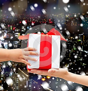 Close up of child and mother hands with gift box