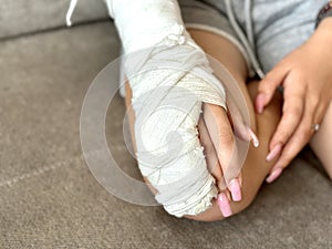 Close-up of a child\'s broken arm in a cast. The girl holds her bent arm.