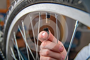 Close-up of child`s hand with cap for bicycle wheel nipple. Pumping tires bike.