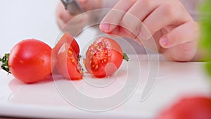 Close-up of a child's hand incorrectly cutting a cherry tomato boy or girl learning to cut vegetables with a