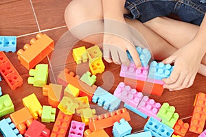 Close up of child`s hand playing plastic toy building blocks, top view from above