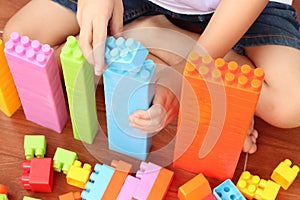 Close up of child`s hand playing plastic toy building blocks, top view from above