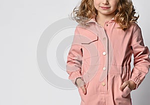 Close-up of a child's hand tucked into the pocket of a casual cotton jumpsuit. Fragment of a photograph of a child