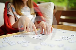 Close-up on child`s hands assembling a jigsaw puzzle on a table