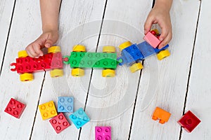 Close up of child`s hands playing with colorful plastic bricks a
