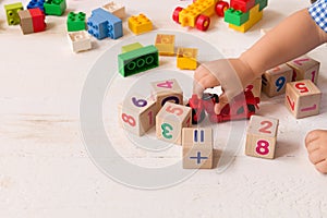 Close up of child`s hands playing with colorful plastic bricks and red motocicle at the table. Toddler having fun