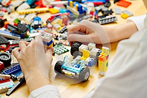 Close up of child& x27;s hands playing with colorful plastic bricks at the table. development of fine motor skills in