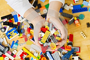 Close up of child& x27;s hands playing with colorful plastic bricks at the table. development of fine motor skills in