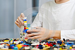 Close up of child& x27;s hands playing with colorful plastic bricks at the table. development of fine motor skills in