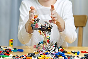 Close up of child& x27;s hands playing with colorful plastic bricks at the table. development of fine motor skills in