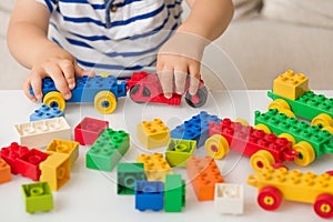 Close up of child`s hands playing with colorful plastic bricks at the table. Toddler having fun