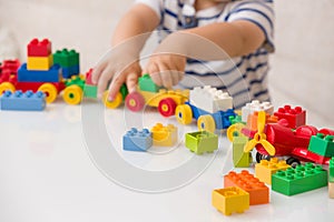Close up of child`s hands playing with colorful plastic bricks at the table. Toddler having fun