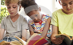 Close Up Of Children Reading On Window Seat