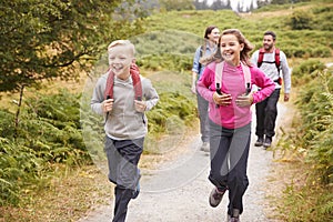 Close up of children running ahead of parents on a country path during a family vacation, front view