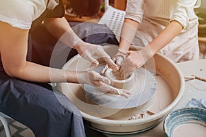 Children`s and adults`s hands together working behind the potter`s wheel