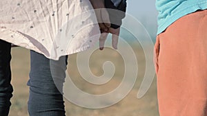 Close-up children's hands holding each other. illegals Gypsies kids from dysfunctional family stand alone in field. Arabs refugees