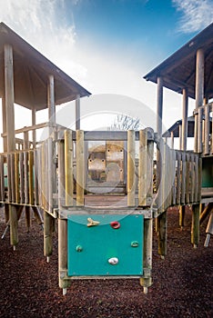 Close up of children's playground wooden play structure fort, climbing wall with grips and bridge.