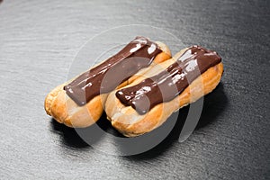 Chocolate eclairs close up on black background.