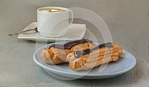 Close up of a chocolate eclairs and cup of espresso