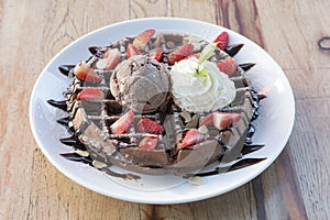 Close up of chocolate ice cream with waffle and fresh strawberry on wood table background