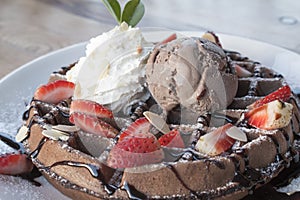 Close up of chocolate ice cream with waffle and fresh strawberry on wood table background