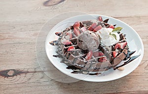 Close up of chocolate ice cream with waffle and fresh strawberry on wood table background