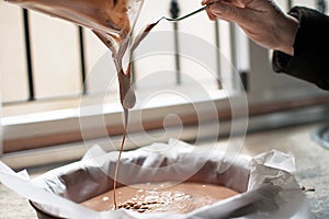 A close-up of chocolate milk liquid being poured into the form of a confectionery syringe in the form mold or mould. Preparation