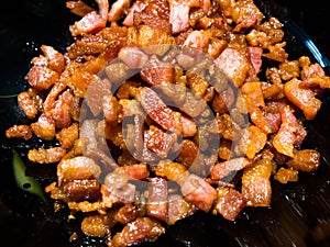 Close-up on chopped, crispy fried bacon on black background