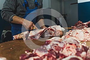Close up of chopped pieces of meat and male hands of butcher in special gloves cutting fresh meat with knife. Meat pork