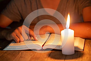 Close up of Christian boys  are reading and study bible In the room and lit candles to light, Religious concepts