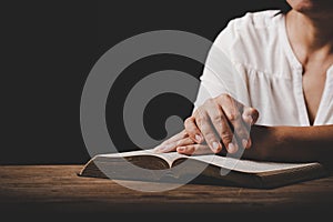 Close up of christian woman hand on holy bible are pray and worship for thank god in church with black background, concept for