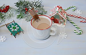Close-up christmas composition with gingerbread cookies, mug of cocoa, caramel canes gingerbread house and decorations on blue
