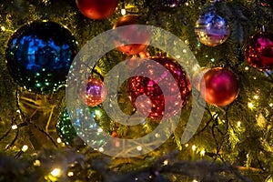 Close-up of a Christmas tree branch with decorative balls, toys and a shining garland. soft focus, background in blur