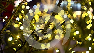 Close-up of Christmas tree branches with snow decorated yellow lights garlands