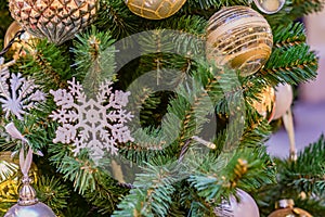 Close up of christmas tree decorated with gold and white balls and snowflake. New year background