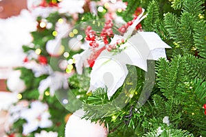 Close up of christmas tree decorated with poinsettia and garland with lights on. Festive background with copy space for your