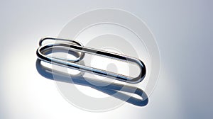 Close-up Of Chrome Paperclip On White Surface